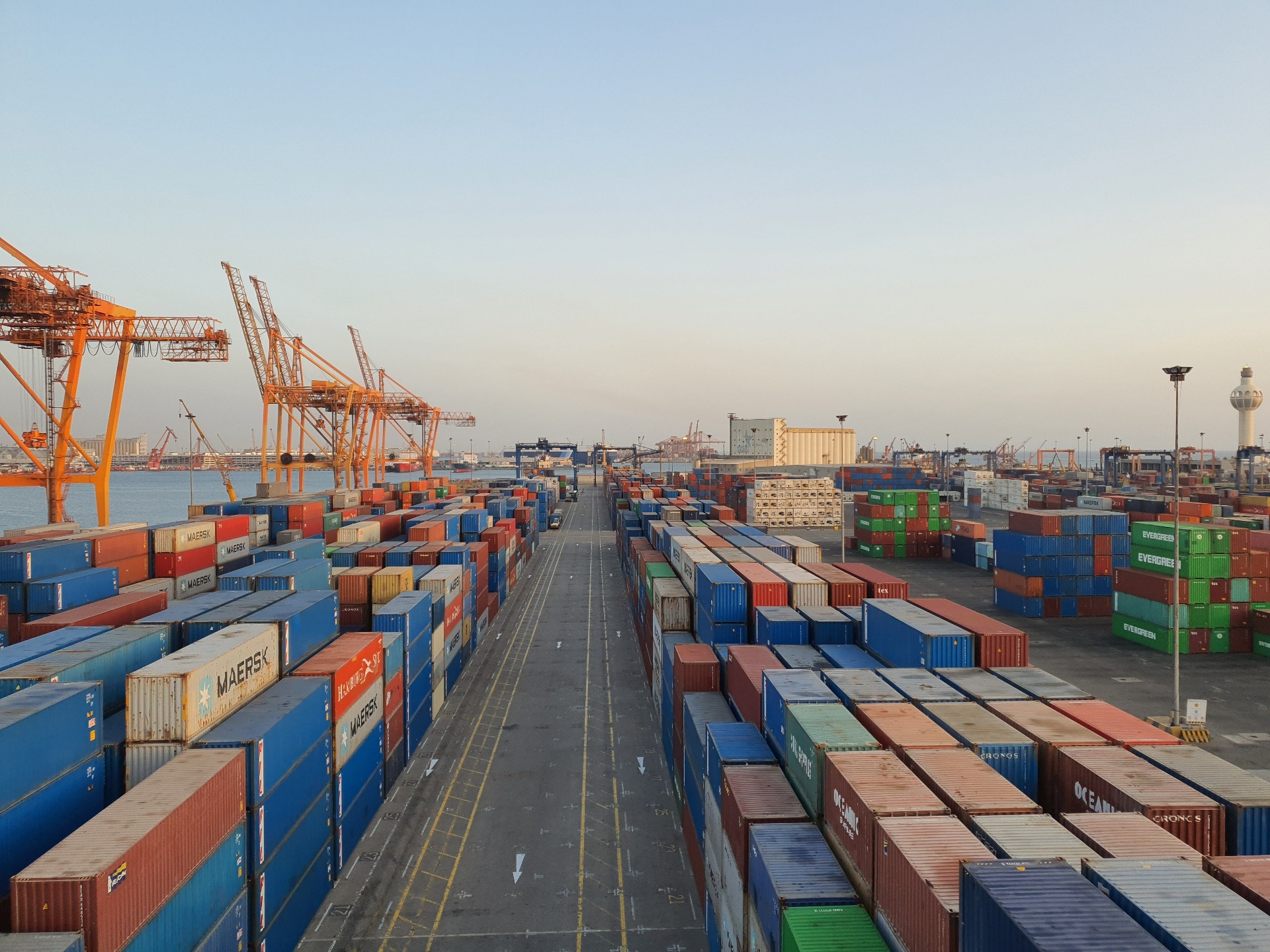 Ships, trucks and planes at a busy port at sunset